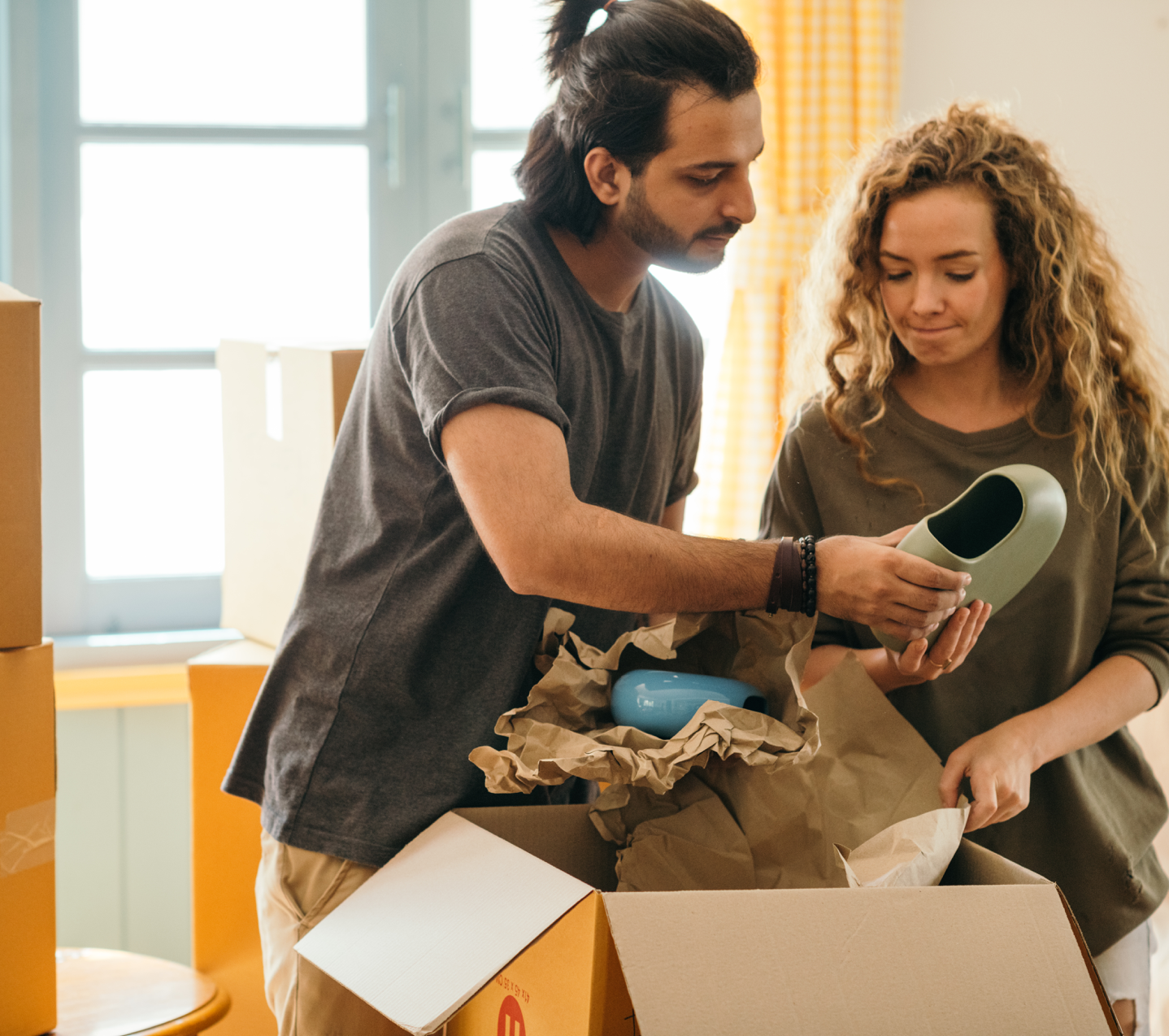 Pensive multiracial couple unpacking vase after renting new apartment